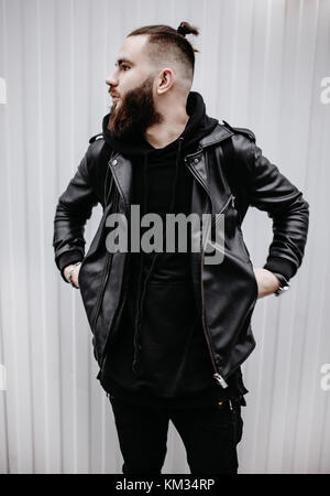 Modern young bearded man in black style clothes standing in urban background. Stock Photo
