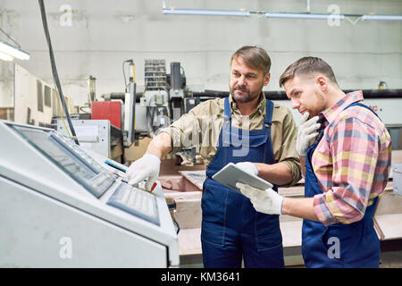 Two Factory Workers Operating Machines Stock Photo