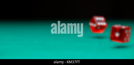 Defocused photo of two dice falling on green table Stock Photo