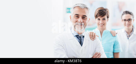Doctors and medical staff posing at the hospital and holding each other's shoulders, teamwork and healthcare banner Stock Photo