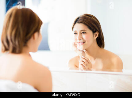 young woman looking on reflection in the mirror at bathroom