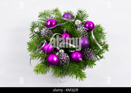 Christmas door wreath with fir branch, silver decorated pine cones, glitter and purple baubles. Stock Photo