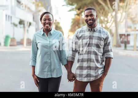 Young African couple smiling while holding hands in the city Stock Photo