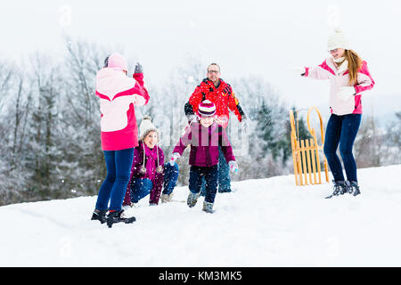 Family with kids having fun witn snowball fight in winter Stock Photo