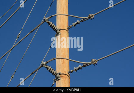 Close up of brand new wood pole and power lines in new development area with insulators against blue sky Stock Photo
