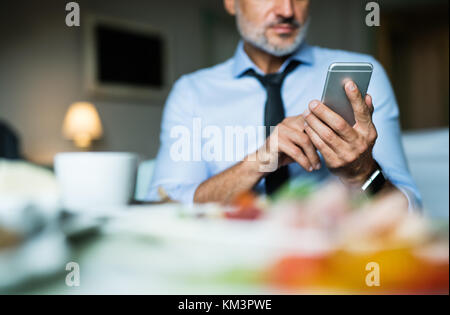 Mature businessman with smartphone in a hotel room. Stock Photo