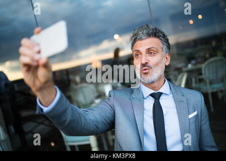 Businessman with smartphone in an outdoor hotel cafe. Stock Photo