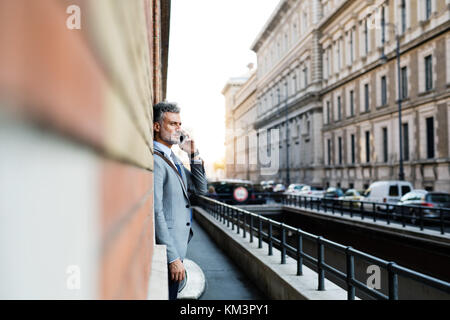 Mature businessman with smartphone in a city. Stock Photo