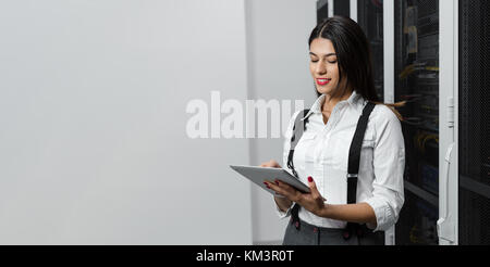 Technician using tablet pc while analysing server in large data center Stock Photo