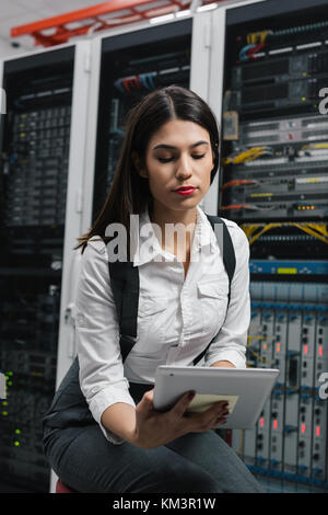 Technician using tablet pc while analysing server in large data center Stock Photo