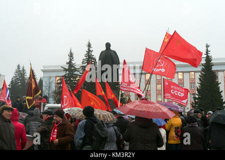 IZYUM, Russia - November 7, 2017. Red flag of Communist party of Ukraine against a monument to Lenin. Monument to Vladimir Ulyanov Lenin and flag of C Stock Photo