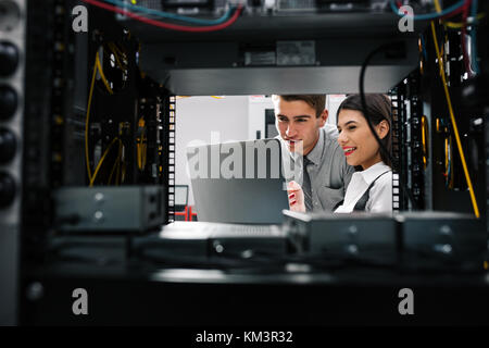 Team of technicians working together on servers at the data centre Stock Photo