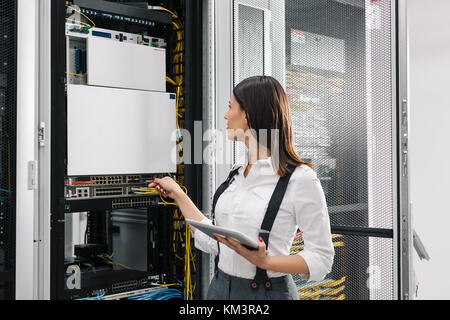 Technician using tablet pc while analysing server in large data center Stock Photo