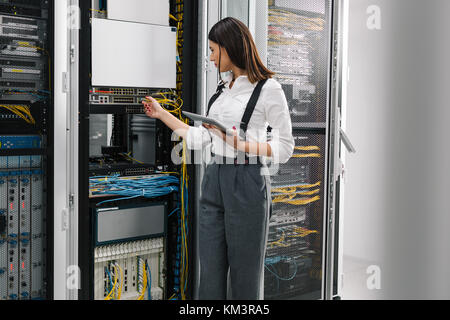 Technician using tablet pc while analysing server in large data center Stock Photo
