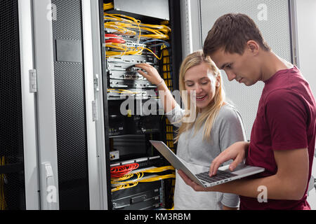 Team of technicians working together on servers at the data centre Stock Photo