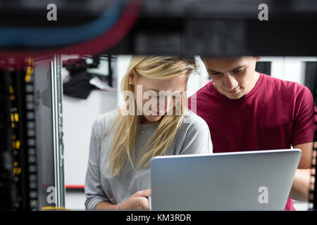 Team of technicians working together on servers at the data centre Stock Photo