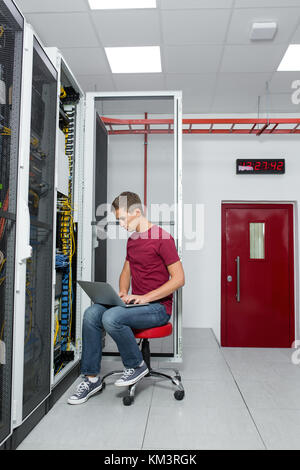 Young man is standing next to the racks with computer equipment Stock Photo