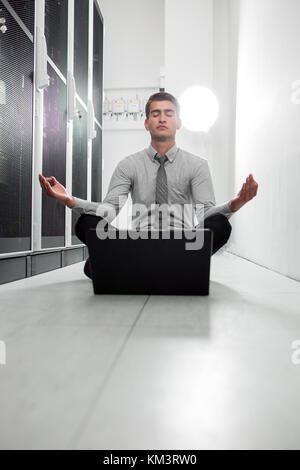 Portrait of modern young man holding laptop standing in server room working with supercomputer Stock Photo