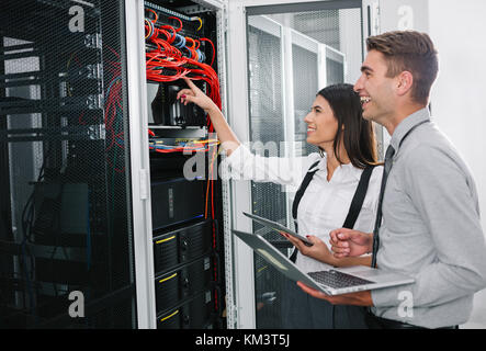 Team of technicians working together on servers at the data centre Stock Photo