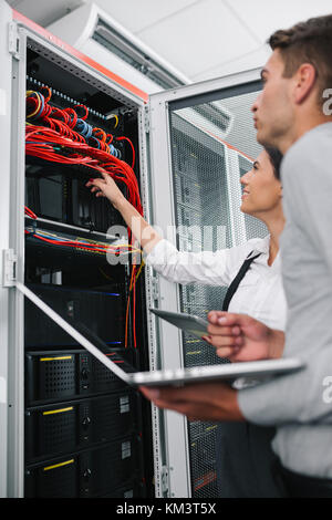 Team of technicians working together on servers at the data centre Stock Photo