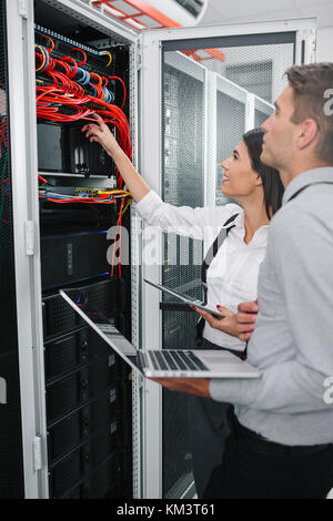 Team of technicians working together on servers at the data centre Stock Photo