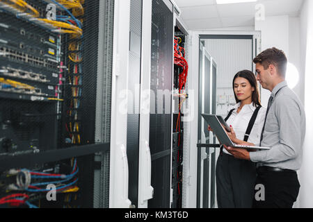 Team of technicians working together on servers at the data centre Stock Photo
