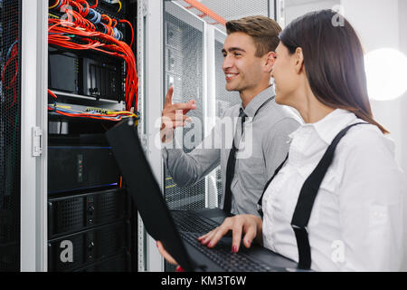 Team of technicians working together on servers at the data centre Stock Photo