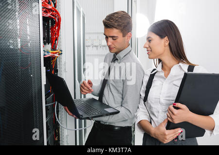 Team of technicians working together on servers at the data centre Stock Photo