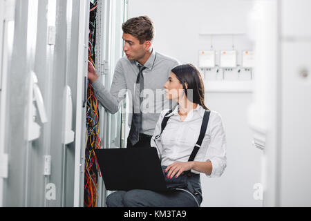 Team of technicians working together on servers at the data centre Stock Photo