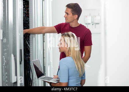 Team of technicians working together on servers at the data centre Stock Photo