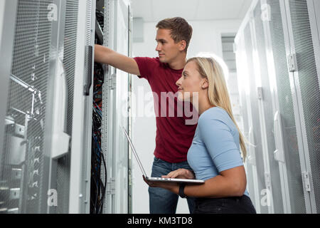 Team of technicians working together on servers at the data centre Stock Photo