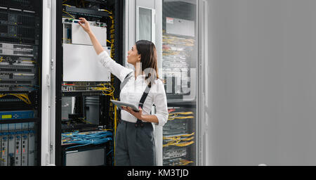 Technician using tablet pc while analysing server in large data center Stock Photo