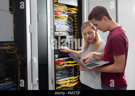 Team of technicians working together on servers at the data centre Stock Photo