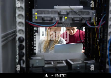 Team of technicians working together on servers at the data centre Stock Photo