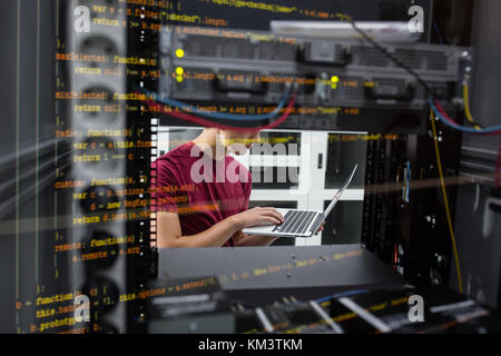 Portrait of modern young man holding laptop standing in server room working with supercomputer Stock Photo