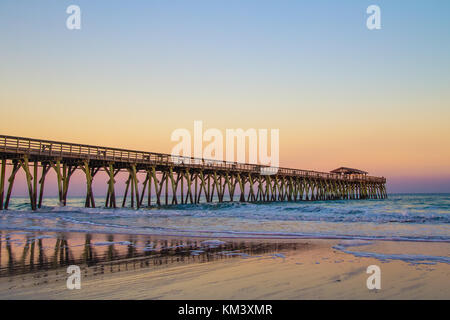 Myrtle Beach, South Carolina Beach. Seascape in Myrtle Beach, South Carolina with long wooden pier and sunset horizon on the Atlantic Ocean. Stock Photo