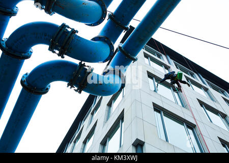 Window cleaner abseiling above pipe structure. Berlin. Germany. Stock Photo