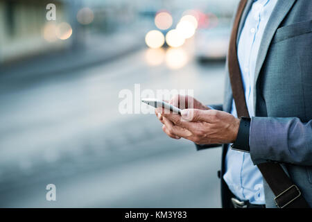 Businessman with smartphone in a city. Stock Photo