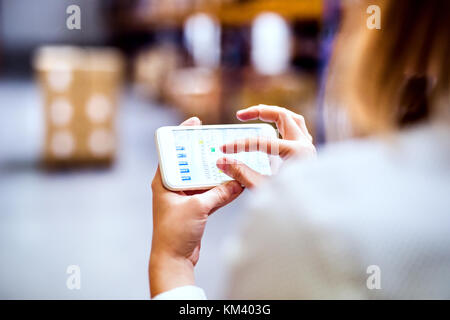 Woman warehouse worker with smartphone. Stock Photo