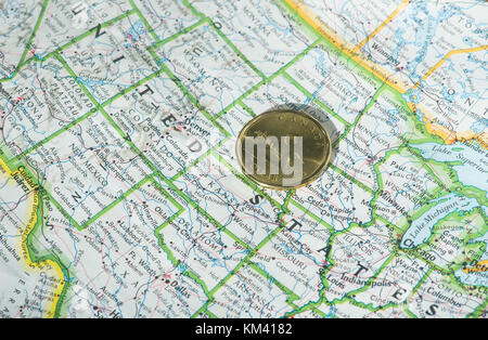 A Canadian one dollar coin is shown on a map of the United States Stock Photo
