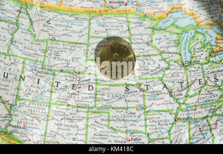 A Canadian one dollar coin is shown on a map of the United States Stock Photo