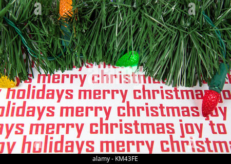 colorful holiday light bulbs glowing with garland on Christmas wrapping paper Stock Photo
