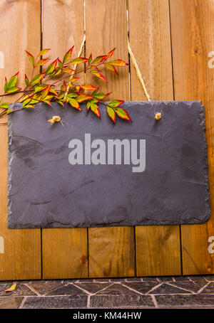 Rustic blank slate noticeboard hanging by twine on a wood background with copy space Stock Photo