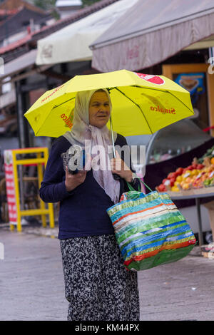 SARAJEVO, BOSNIA AND HERZEGOVINA - AUGUST 20 2017: Old woman selling umbrellas in the street of Sarajevo Stock Photo