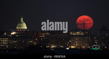 A giant orange super moon rises over the U.S. Capitol and skyline December 3, 2017 in Washington, DC. The full Moon is the first of three consecutive supermoons expected over the next two months. Stock Photo