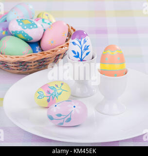 Decorative Easter eggs on a plate with egg cups and basket Stock Photo