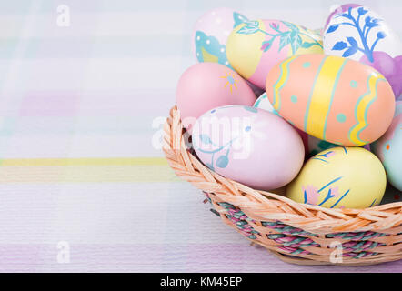 Basket of colorful Easter eggs on a pastel colored surface Stock Photo