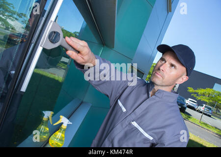 Man using squegee to clean windows Stock Photo