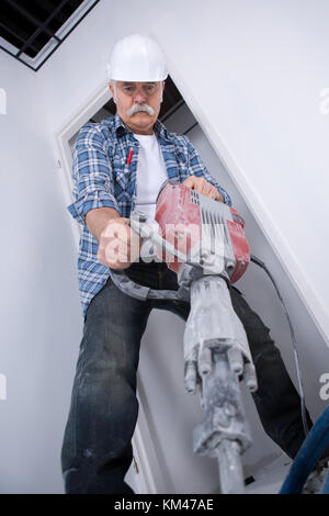 Senior man using jackhammer Stock Photo