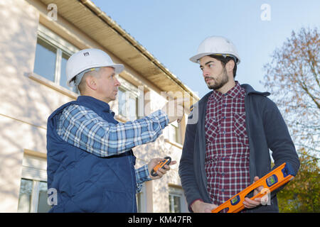 builders in hardhats talking outdoors Stock Photo